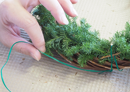 リース台にグリーンを植え込む