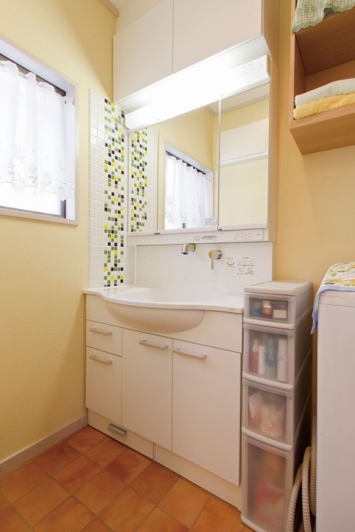 キッチンとトータルコーディネートしたモザイクタイルが特徴の洗面所