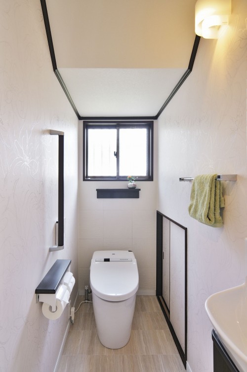 白いクロスに手すりやモールディング材をダークブラウンに統一したトイレ