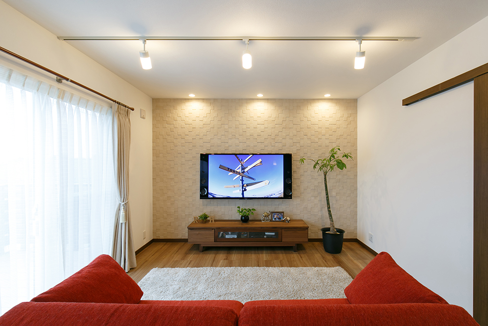 リビングに赤いソファとエコカラットに壁掛けテレビのシンプルなリビングリフォーム事例