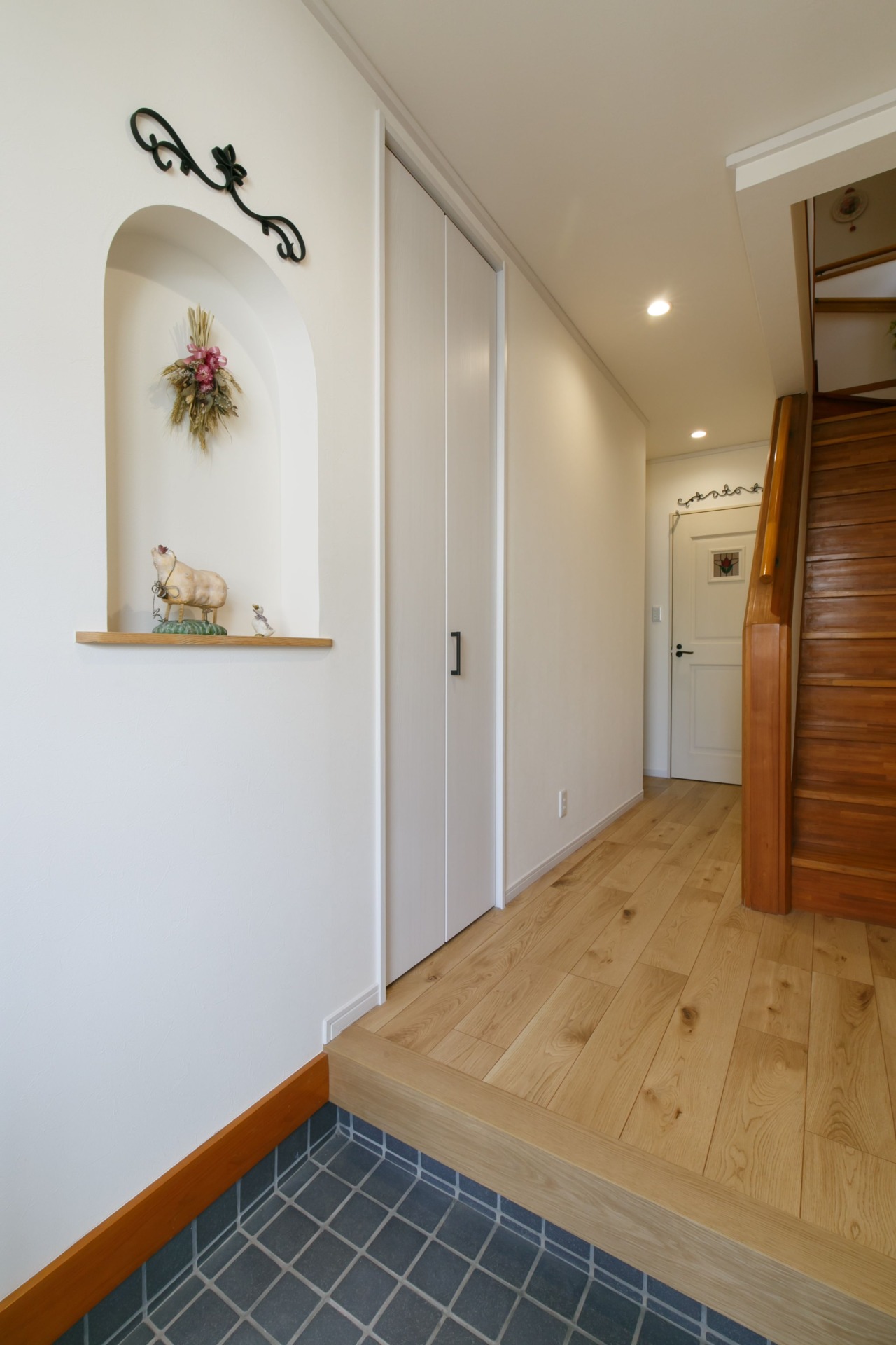 横浜市の戸建カントリーリノベーション 天然木のナチュラルな床材にキャンドールの洗面台や玄関の造作ニッチおしゃれな事例（玄関）