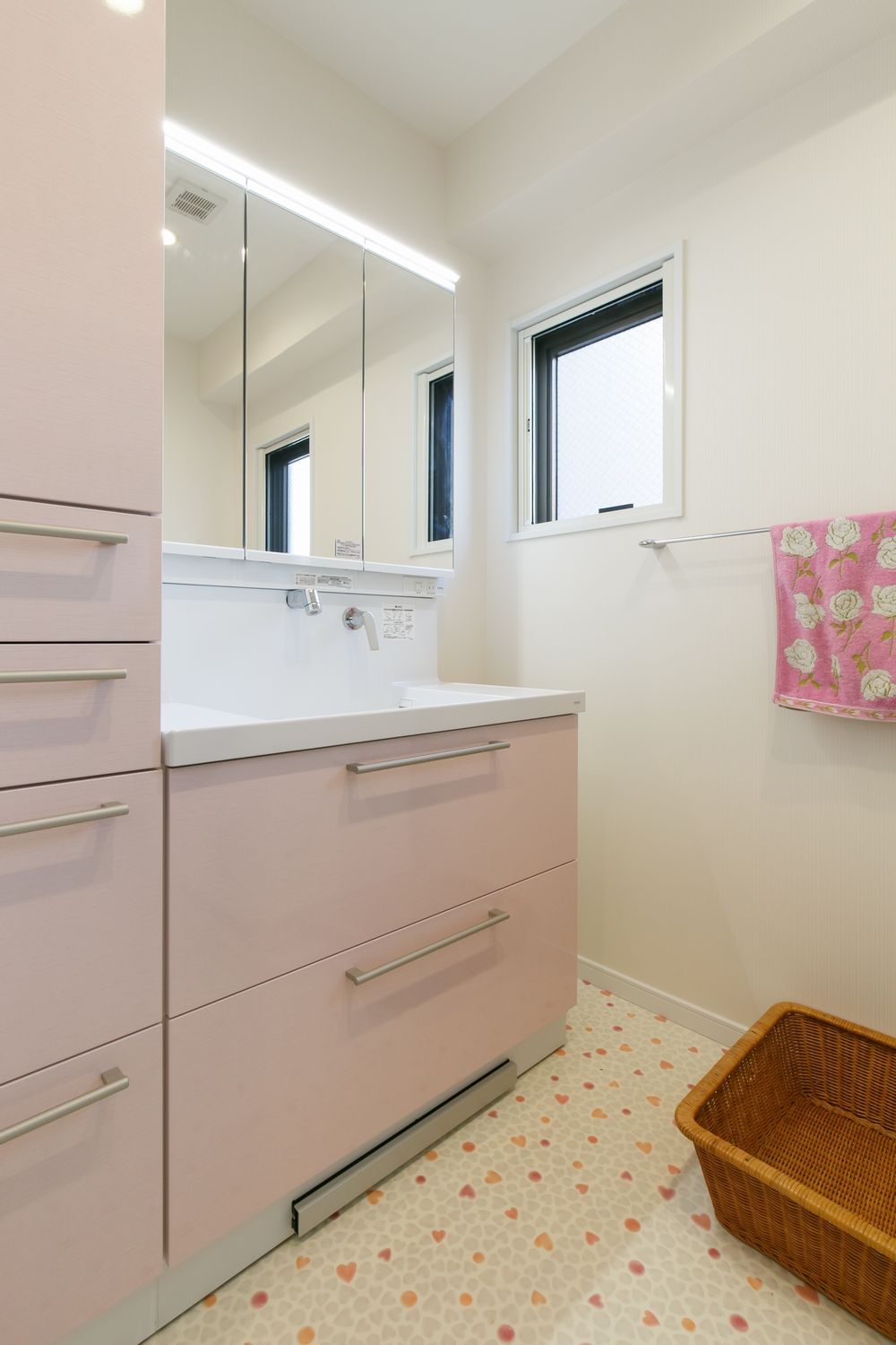 ハート柄の床材とピンクの扉柄がかわいい洗面リフォーム事例