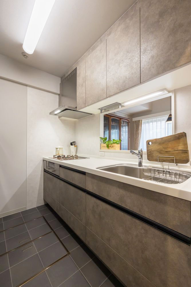 石目調のグレーの扉と白いワークトップが上品なキッチン。黒いタイル床との組み合わせがスタイリッシュ